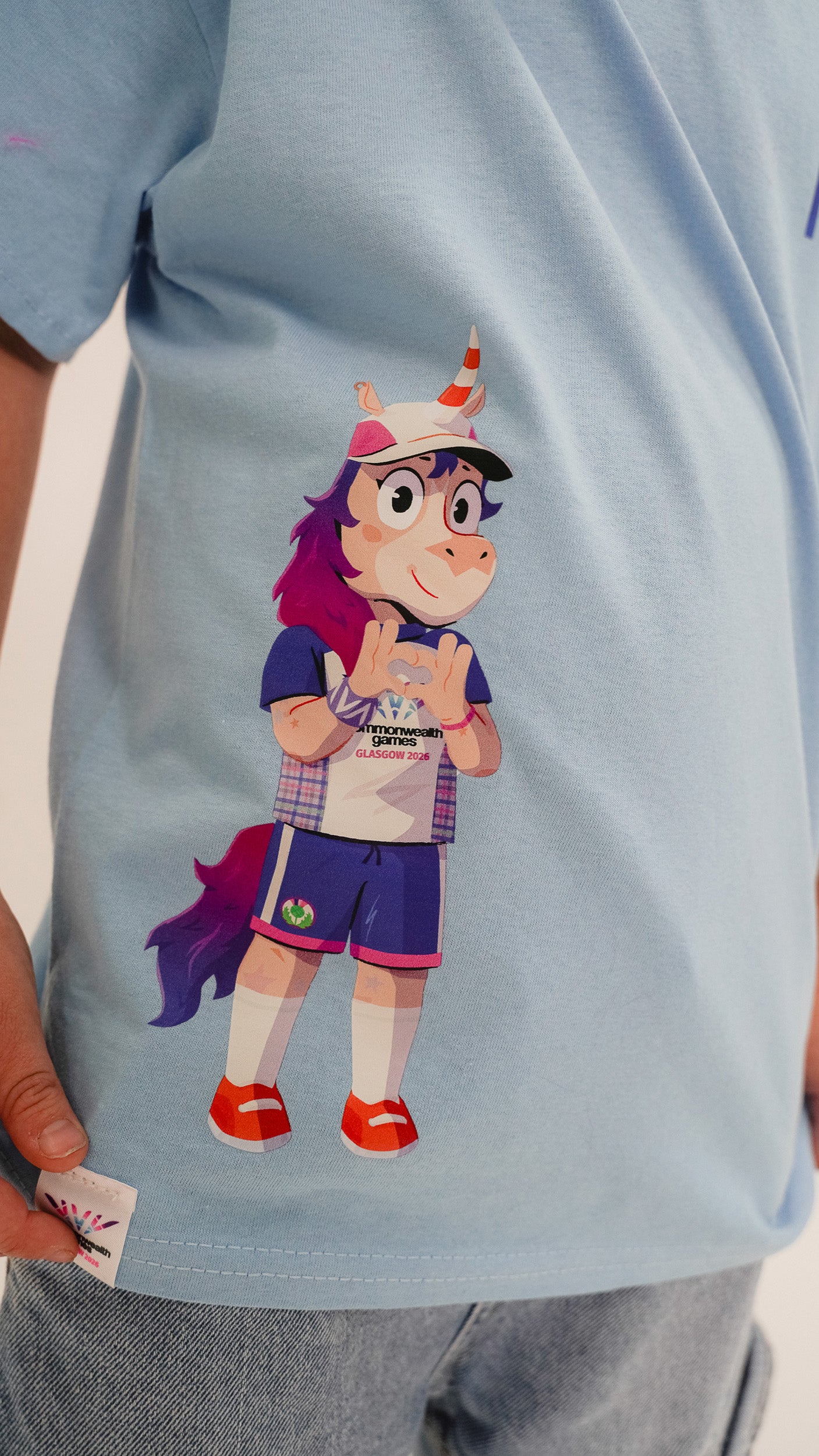 Close up of young boy wearing t-shirt showing Glasgow 2026 Finnie Mascot side print detail.