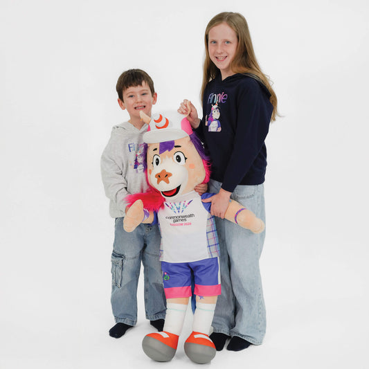 A young boy and girl holding a 1 metre Glasgow 2026 Finnie mascot between them
