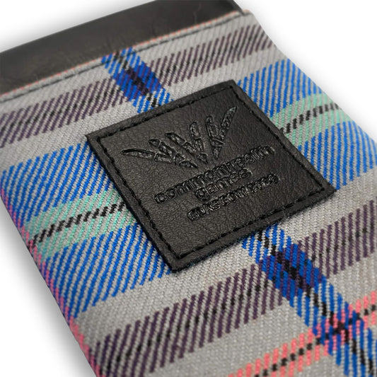 Close up view of Glasgow 2026 Tartan Glasses Sleeve on grey background showing debossed logo detail
