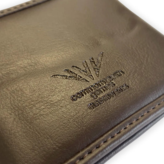Closeup view of Glasgow 2026 Country Green Harris Tweed Men's Wallet on grey background showing debossed logo detail.