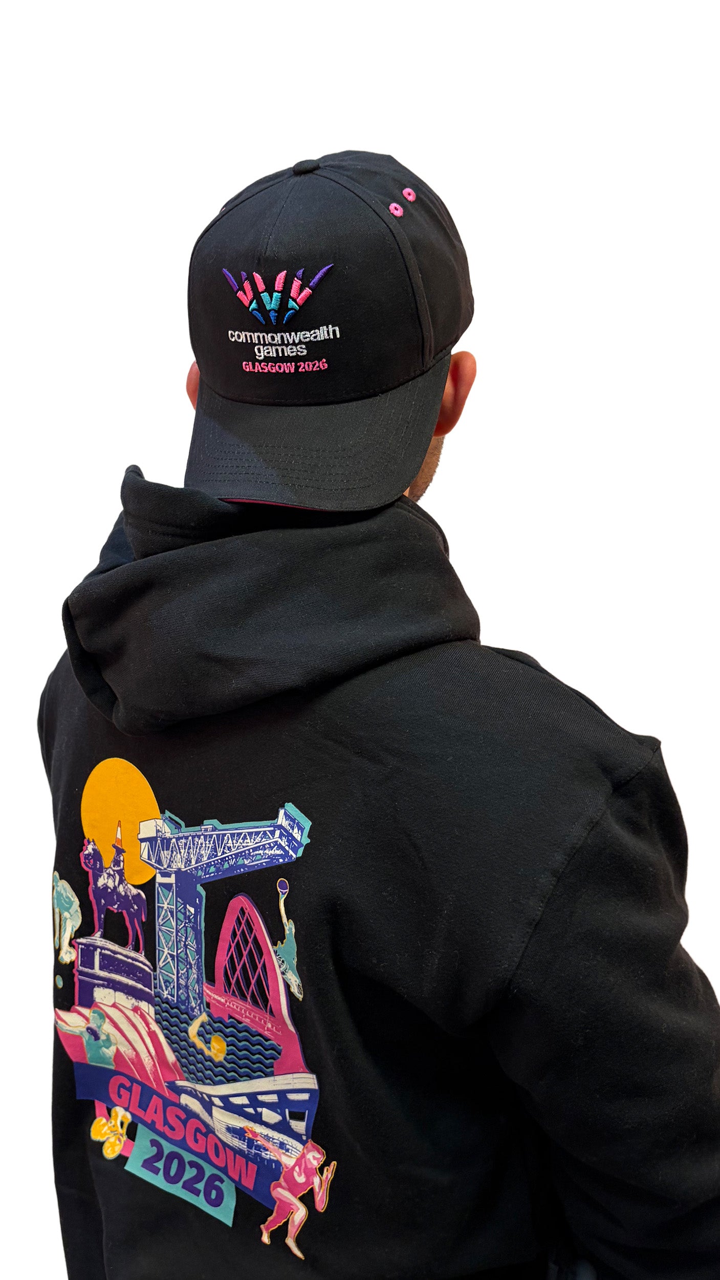 Back view of man wearing  black baseball cap with pink sandwich peak and full colour Glasgow 2026 logo.