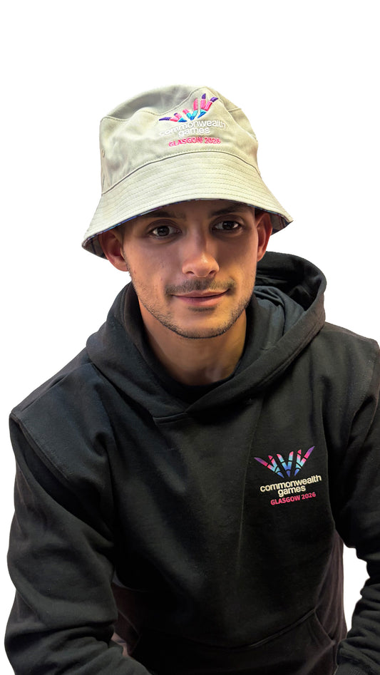 Man wearing grey reversable bucket hat with Glasgow 2026 logo.