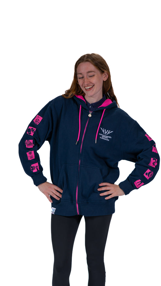 Front view of woman wearing contrast navy/pink hoodie with mono Glasgow 2026 logo on the left chest and sports pictograms on the arms.