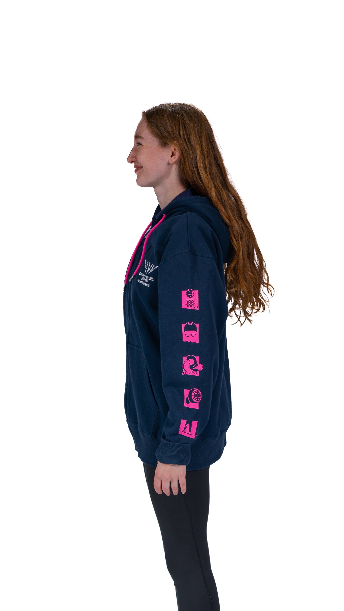 Side view of woman wearing contrast navy/pink hoodie with mono Glasgow 2026 logo on the left chest and sports pictograms on the arms.