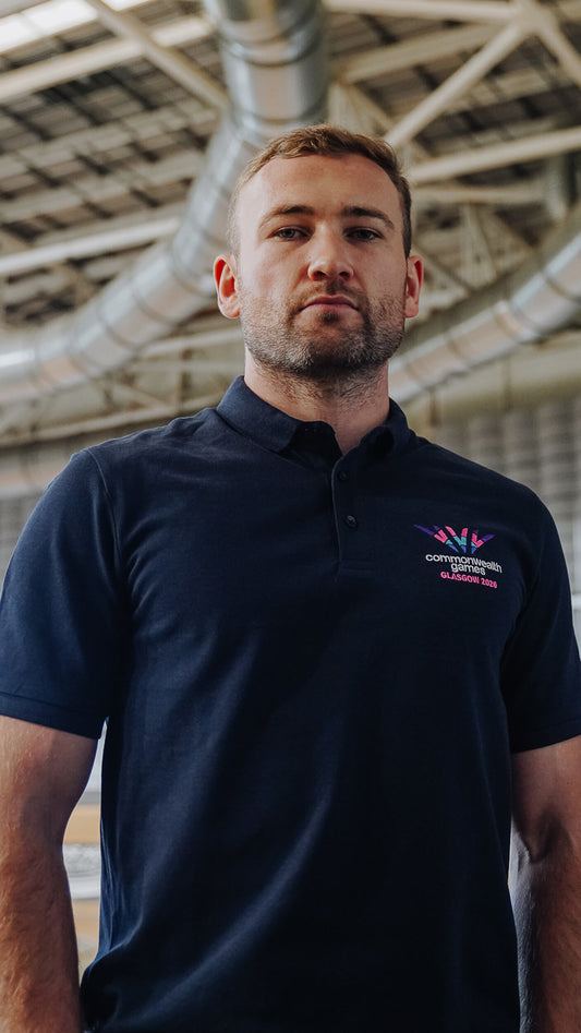 Man wearing navy polo shirt with full colour embroidered Glasgow 2026 logo.