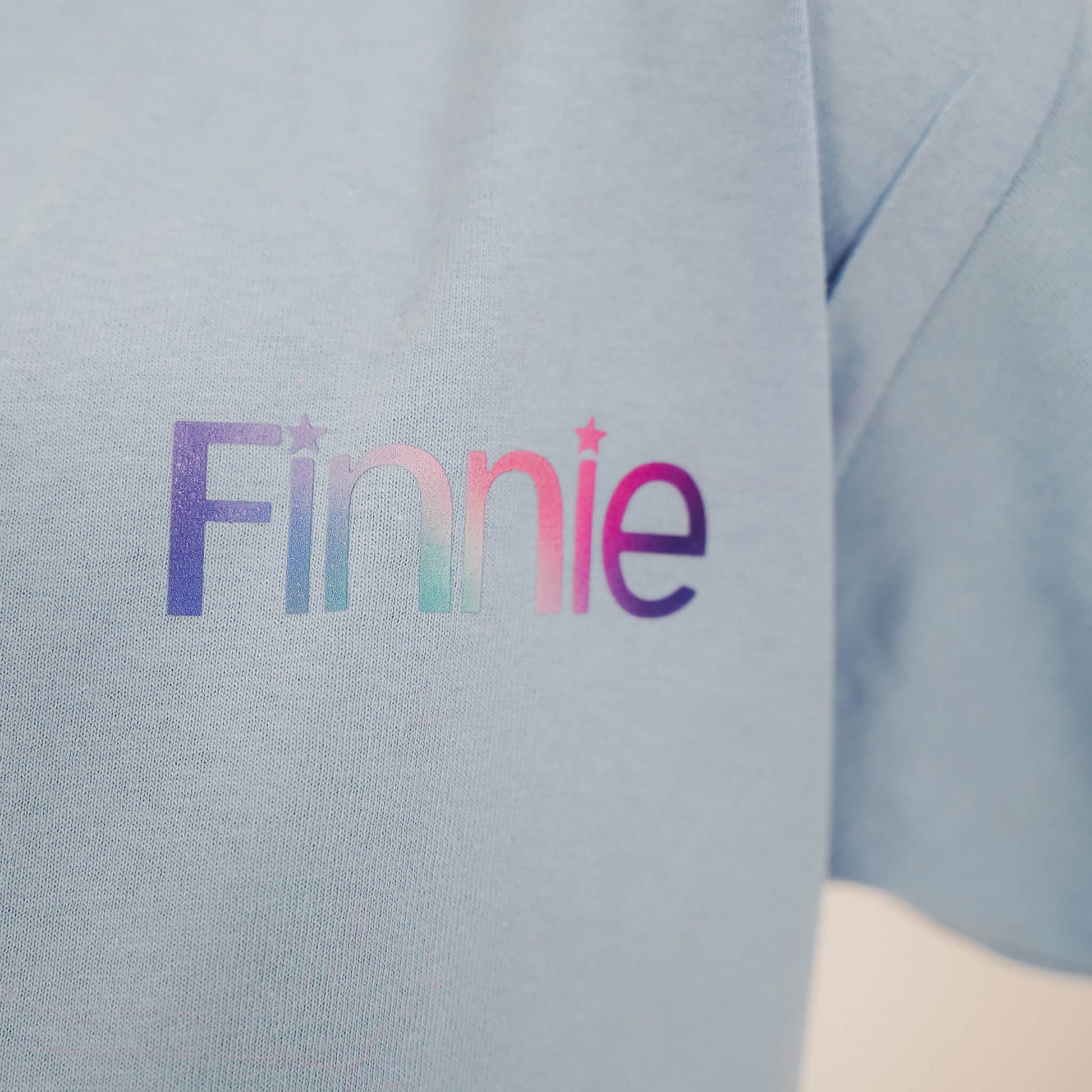Close up of Finnie name print on left chest of blue t-shirt - Glasgow 2026