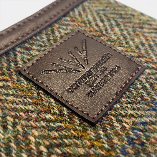 Close up view of Glasgow 2026 Country Green Harris Tweed Coin Purse on grey background showing debossed logo detail