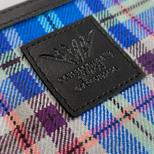 Closeup view of Glasgow 2026 Lambswool Tartan Coin Purse on grey background showing debossed logo detail